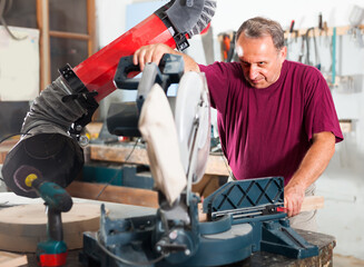 Carpenter cutting a wooden workpiece on an electical circular saw. High quality photo