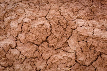 Close up image of brown dry soil texture. Abstract pattern of red-hot cracked clay. Lifeless desert background.