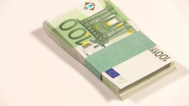 Man's hand leaves a wad of one hundred euro bills on the table