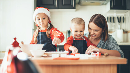 Happy caucasian family preparing cookies for christmas at home waring santa clothes and hat