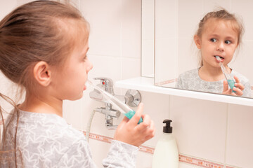 Cute little girl brushing her teeth in the bathroom