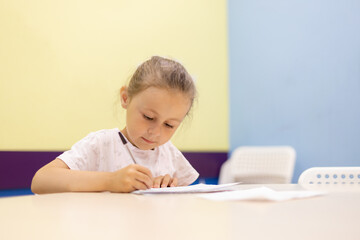 Young girl taking notes in class at school bending over his paperwork