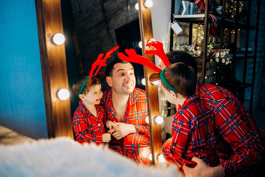 Happy Family Getting Ready For Christmas. Father, Mother And Little Son In Red Plaid Pajamas At Home.