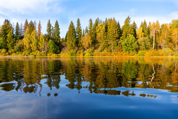Panoramic view of the autumn forest with reflection on the calm water of the lake. Welcome to Russia!