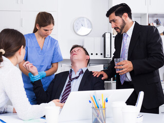Fototapeta na wymiar Businessman in fainting receiving first aid at workplace in office.
