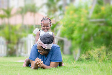 Cheerful african american girl playing on the back of her mother, Happy mother and daughter laughing together outdoor