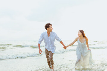Young couple holding hands and running on the beach.