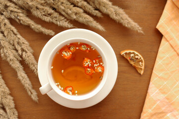 cozy autumn Breakfast with useful tea, honey, cinnamon sticks, lemon, dogrose berries and bouquet of dried flowers and cotton orange napkin for serving, selective focus