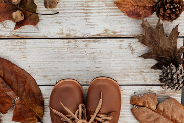 Autumn background with brown shoes and natural leaves on wooden table, seasonal pattern as mockup or banner