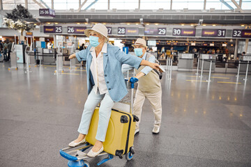 Aged man wheeling a female passenger on a baggage cart