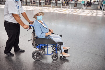 Female tourist in a protective mask sitting in a wheelchair