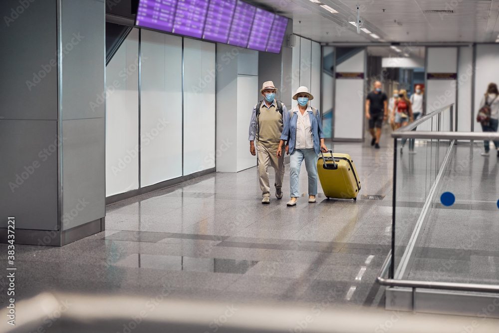 Sticker Elderly tourist couple with luggage walking ahead