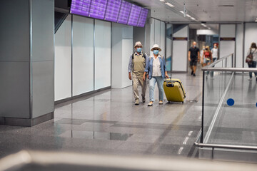 Elderly tourist couple with luggage walking ahead