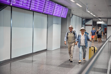 Joyful married couple walking along the airport terminal