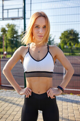 Young athletic woman with perfect body in sportswear training in the city park. Fitness sportwoman in fashion sportswear doing exercise outdoors