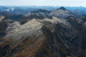 Obraz premium Amazing aerial view harsh mountain range and dramatic sky on the scenic flight from Milford Sound to Queenstown through Mount Aspiring and Fiordland National Park, New Zealand