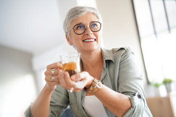 portrait of a beautiful 55 year old woman with white hair drinking a tea