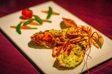 a whole grilled lobster with a  tomato, snow peas and baby carrots on the side