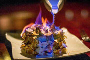 a burnt alaska or bombe alaska flambe on a plate with berries on the side
