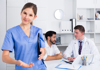 Female doctor making welcome gesture, politely inviting patient in medical office