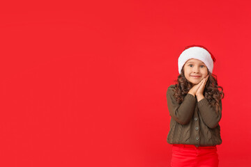 Cute little girl in Santa hat on color background