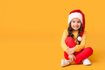 Cute little girl in Santa hat on color background