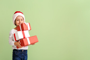 Cute little boy in Santa hat and with gift boxes on color background