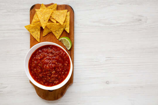 Homemade Tomato Salsa And Nachos On A Rustic Wooden Board On A White Wooden Background, Top View. Flat Lay, Overhead, From Above. Space For Text.