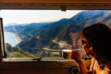 Woman in rv enjoy coast view, drinking coffee
