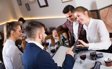 Young people sitting at table in cozy restaurant, discussing menu