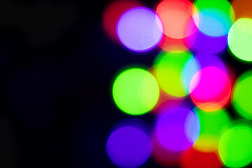 Multi-colored glares side on a black background with room for copyspace text. Festive New Year's background. Bokeh.