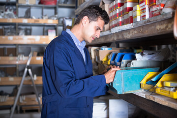 Salesman is checking small details in boxes in the building store.