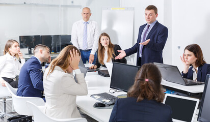 Serious manager expressing dissatisfaction with teamwork of colleagues at meeting