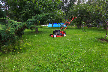 Obraz na płótnie Canvas Blurred background of the home garden and lawn mower on mown grass.