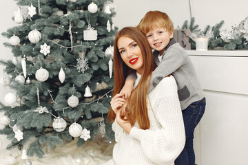 Beautiful mother in a white sweater. Family in a christmas decorations. Little boy in a room