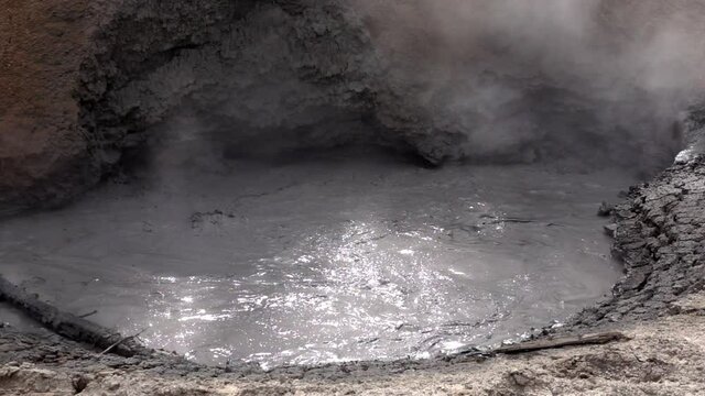 Turbulent mud and steam from a geothermal mud pot in slow motion, at Yellowstone National Park.
