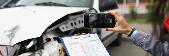 Insurance agent takes pictures of crashed car on his smartphone and fills out the insurance....