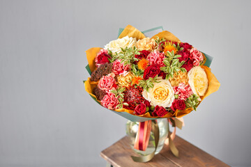 Autumn, Red tones Beautiful bouquet of mixed flowers in womans hands. the work of the florist at a...