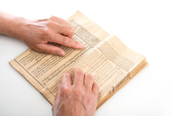 The old man is flipping through an old yellowed book