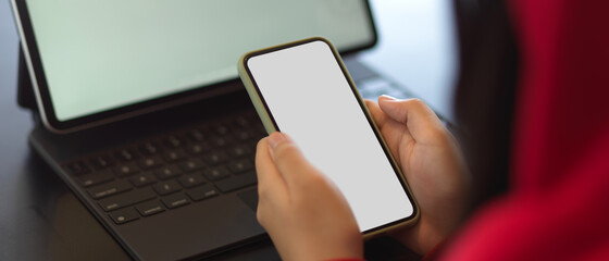 Female hands holding mock up smartphone while working with mock up tablet