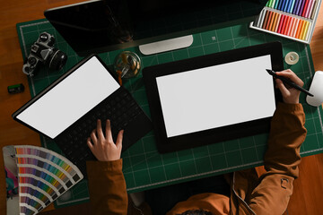 Female graphic designer working with mock up tablet and laptop on computer desk