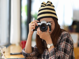 Portrait of female teenager taking photo with digital camera