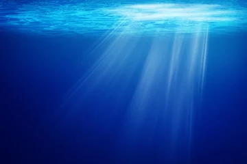 Poster Abstract image of Tropical underwater dark blue deep ocean wide nature background with rays of sunlight. © Angkana