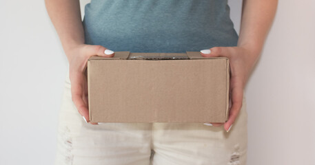  The girl received the package. A young woman with a beautiful manicure holds in her hands and wants to open a box with a parcel. Delivery concept