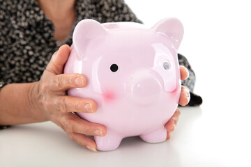 Old lady with yellow skin holding a piggy bank