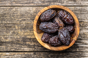 Dried dates fruit in wooden bowl.