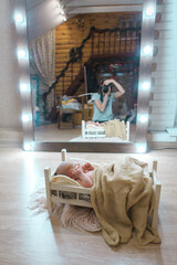newborn photo shoot: a small child is lying on a wooden bed under a blanket. the photographer's reflection in the mirror