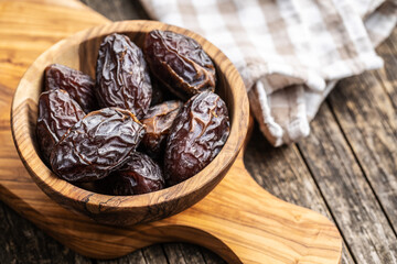 Dried dates fruit in wooden bowl.