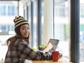 Woman working with tablet while looking and smiling to the camera