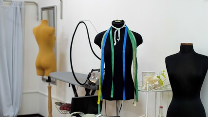 Several headless mannequins stand in a sewing workshop. Centimeters ribbons or measuring tape...